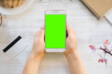 Smartphone ve kredi chroma anahtar üstten görünüm için kız smartphone yeşil ekran elinde kart borç. Internet ticaret ve ödemeler için mal ve Hizmetleri Internet üzerinden online alışveriş için