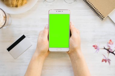 Smartphone ve kredi chroma anahtar üstten görünüm için kız smartphone yeşil ekran elinde kart borç. Internet ticaret ve ödemeler için mal ve Hizmetleri Internet üzerinden online alışveriş için