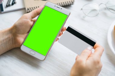 Smartphone ve kredi borç kart kız smartphone yeşil ekran için chroma anahtar elinde. Internet ticaret ve ödemeler için mal ve Hizmetleri Internet üzerinden online alışveriş için