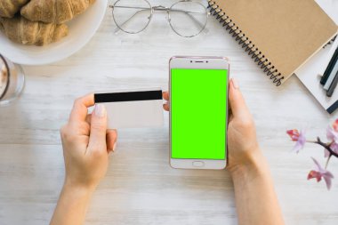 Smartphone ve kredi chroma anahtar üstten görünüm için kız smartphone yeşil ekran elinde kart borç. Internet ticaret ve ödemeler için mal ve Hizmetleri Internet üzerinden online alışveriş için
