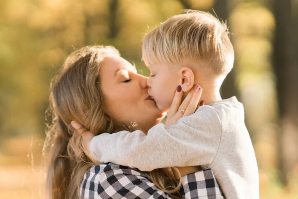 Felice bambino ragazzo baci con mamma nel parco giocare al sole — Foto Stock