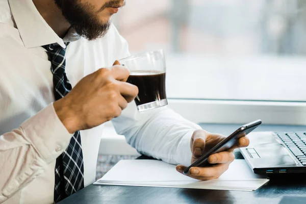 Business man looking at phone texting sms message text drinking coffee on morning break at work office. Businessman lifestyle.