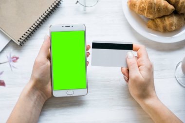 Smartphone ve kredi chroma anahtar üstten görünüm için kız smartphone yeşil ekran elinde kart borç. Internet ticaret ve ödemeler için mal ve Hizmetleri Internet üzerinden online alışveriş için