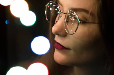 Karanlık ve bokeh güzel beyaz kızla gözlük bir moda portre. Netlik düşük yoğunluklu odak etkisini.