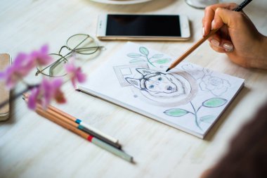 Bir kız bir kafede Beyaz ahşap masa ışık arka plan üzerinde beyaz bir kağıda kalemler Husky ile boyama