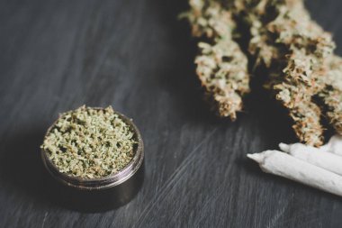 Makro esrar trichomes ve ezilmiş ot ve haddelenmiş ortak bir canapis siyah bir masada doğramak bir değirmeni