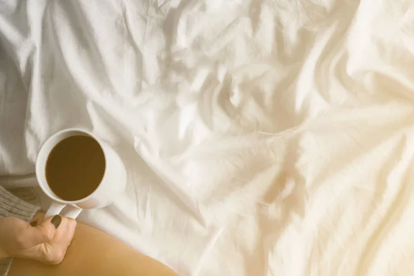 Dziewczyna picia porannej kawy na tablecie białe łóżko czytania w wysokiej Pończochy kopia miejsce top Zobacz barwienia światło żółty — Zdjęcie stockowe