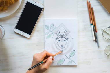 Yakın kadar mı kalemler Husky bir kafede Beyaz ahşap masa ışık arka plan üzerinde beyaz bir kağıda ile boyama