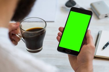 Adam bir smartphone ile kullanan bir ile yeşil perde chroma anahtar birleştirme içecekler kahve haber okumak için. Mobil cihazlar, mobil versiyonu sitedeki demolar kullanımının kavramları