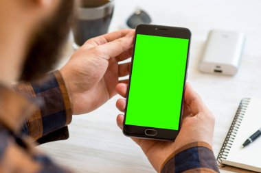 Beyaz zemin üzerinde bir adam elinde chroma anahtar kompozisyon için yeşil ekran siyah bir smartphone