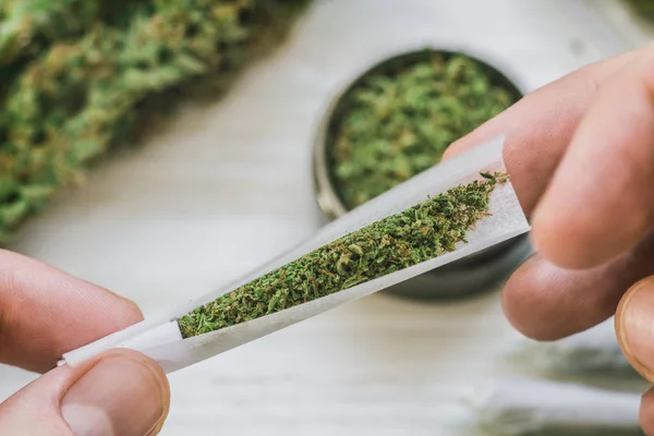 Man rolled Brotes articulares de marihuana, hierba desenrollada sobre un fondo blanco vista superior cerrar — Foto de Stock