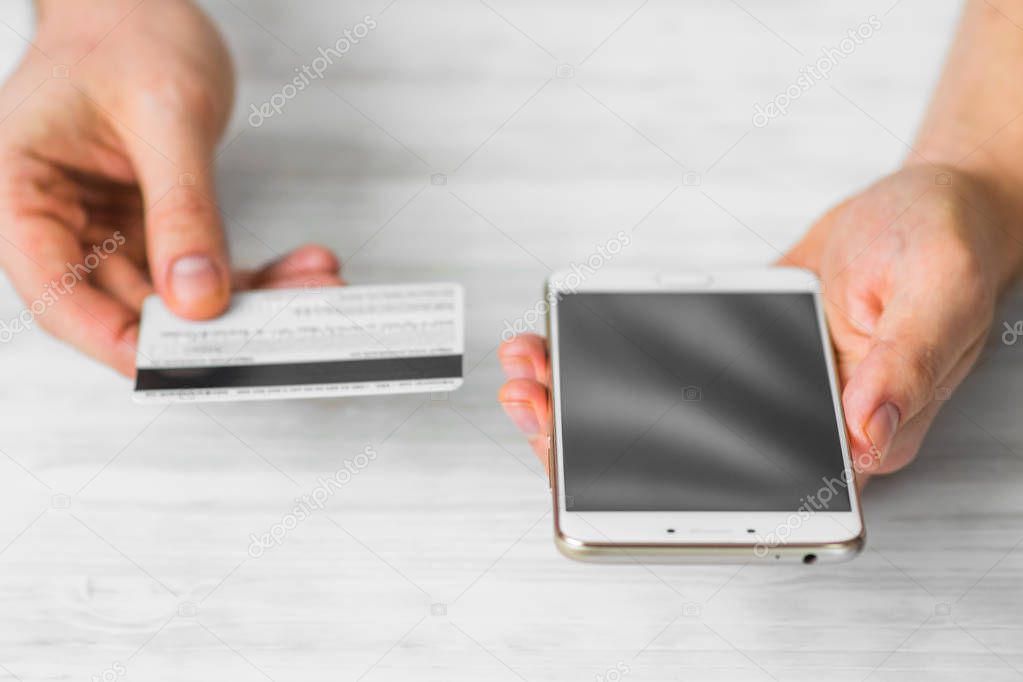 smartphone and credit card in the hands of a man on a white background, concepts of Internet commerce and the use of online banking to pay for services and goods