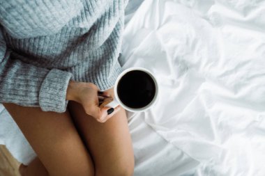 yatakta fincan kahve kopya alanı yukarıdan tutarak yün kazak giyen kız