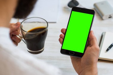 Adam bir akıllı telefon ile yeşil ekran chroma anahtar birleştirme içecekler kahve haber okumak için kullanır. Mobil cihazlar, mobil versiyonu sitedeki demolar kullanımının kavramları