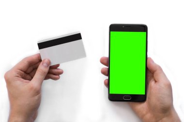 Chroma anahtar kompozisyon ve beyaz bir arka plan üzerinde bir adam elinde bir kredi kartı için yeşil ekran ile akıllı telefon, Internet, üstten görünüm Internet ticareti için online banka öder. izole