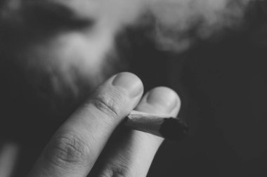 sigara esrar, bir adam elinde ortak ot. Siyah bir arka plan üzerinde duman. Tıbbi esrar kullanım ve yasallaştırma esrar kavramları. Siyah ve beyaz