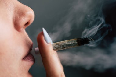 Bir kadın sigara esrar esrar, esrar ve onun elinde bir çakmak. Siyah bir arka plan üzerinde duman. Tıbbi esrar kullanım ve yasallaştırma esrar kavramları.