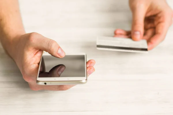 Manos de un teléfono inteligente hombre y tarjeta de crédito en el en una espalda blanca — Foto de Stock