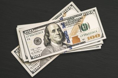 Bize yeni bir siyah ahşap dokulu masaya yüz dolarlık banknotlar. Yukarıdan görüntüleyin. Para ve Finans 100 kavramları
