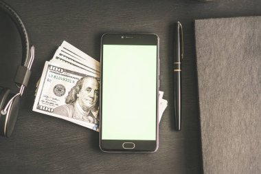 Chromakey anahtarlama ve mockup bir siyah dokulu ahşap tablo yüz dolar banknotlar ABD ile kalem, kitap ve kulaklık ile Smartphone. 