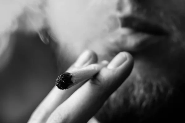 男の手で共同します。男喫煙大麻ウィード。黒の背景にたばこを吸います。医療マリファナの使用と大麻の合法化の概念。黒と白 — ストック写真