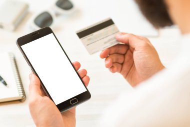 Siyah smartphone kadar alay etmek ve bir kredi kartı tutan smartphone Closeup fotoğraf iş adamı elinde el kredi kartı ve. Online ödeme plastik kart. Yatay mockup. Bulanık, film etkisi