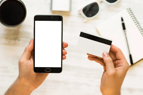 holding hand credit card and using smartphone. A black smartphone mock up and a credit card in the hands of Closeup photo businessman Online payments plastic card. Horizontal mockup