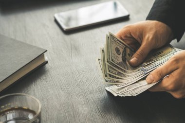 Beyaz genç işadamı para sayar, yüz dolar faturaları bir siyah arka plan yakın plan, Motion blur. İş ve finans kavramları.