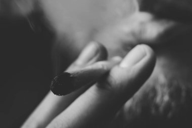 el A adam ortak bir esrar ot çekiyor. Siyah bir arka plan üzerinde duman. Tıbbi esrar kullanım ve yasallaştırma esrar kavramları. Siyah ve beyaz