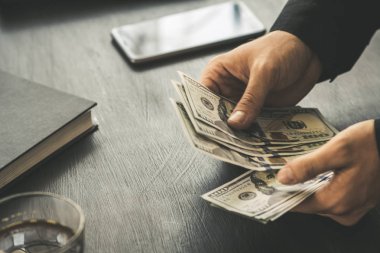 Beyaz genç işadamı para sayar, yüz dolar faturaları bir siyah arka plan yakın plan, Motion blur. İş ve finans kavramları.