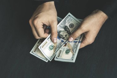 Beyaz genç adam para sayar, yüz yeni banknotlar siyah bir arka plan planı kapatın. İş ve finans kavramları. Üstten Görünüm .