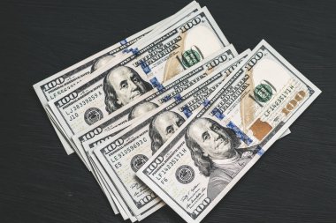 Bize yeni bir siyah ahşap dokulu masaya yüz dolarlık banknotlar. Yukarıdan görüntüleyin. Para ve finans kavramları