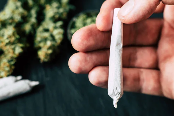 Hengerelt közös, a marihuána, a kezében egy férfi ellen a marihuána legalizálása és a cannabis gyógyászati célú fogalmának — Stock Fotó