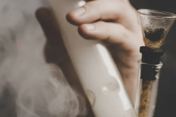 A man smokes bong cannabis weed. Smoke on a black background. Concepts of medical marijuana use and legalization of the cannabis. — Stock Photo, Image