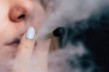 Bir kadın sigara esrar esrar, esrar ve onun elinde bir çakmak. Siyah bir arka plan üzerinde duman. Tıbbi esrar kullanım ve yasallaştırma esrar kavramları.