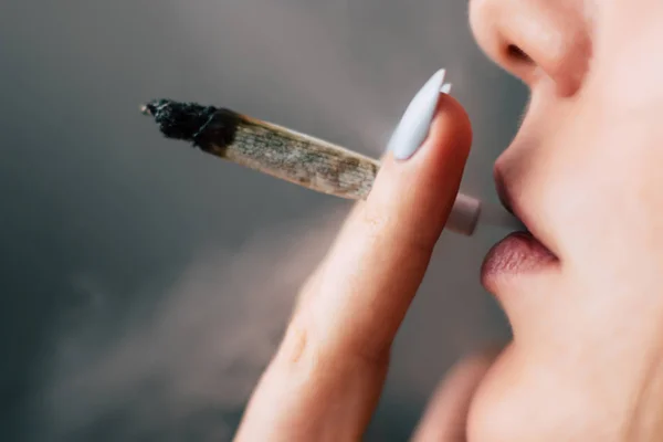 Fuma maconha, um charro e um isqueiro nas mãos. Fumar em um fundo preto. Conceitos de uso medicinal de maconha e legalização da cannabis . — Fotografia de Stock