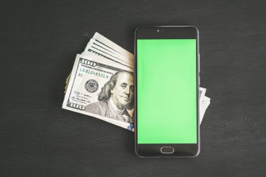 Smartphone ile chromakey anahtarlama ve bir siyah mockup için yüz dolar banknotlar ABD ile ahşap masa dokulu. Yeni Finans teknolojileri ve iş haberleri kavramları. Yatay