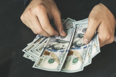 Beyaz genç işadamı para sayar, yüz dolar faturaları bir siyah arka plan yakın plan, Motion blur. İş ve finans kavramları. Üstten Görünüm 100