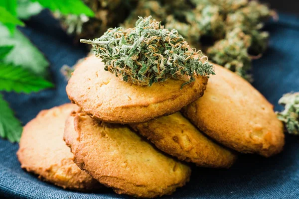 Närbild av Cookies med cannabis och knoppar av marijuana på bordet. En burk med cannabis knoppar begreppet matlagning med cannabisblad. Behandling av medicinsk marijuana för användning i livsmedel, på en svart bakgrund — Stockfoto