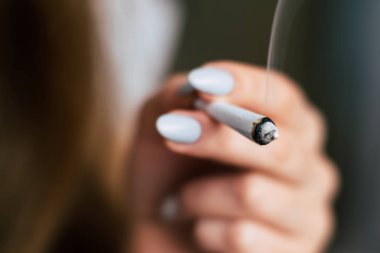 elinde ortak. Bir kadın esrar ot çekiyor bir. Siyah bir arka plan üzerinde duman. Tıbbi esrar kullanım ve yasallaştırma esrar kavramları.