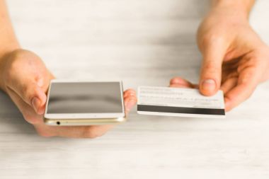 bir adam siyah bir akıllı telefon elinde kredi kartı ve bir