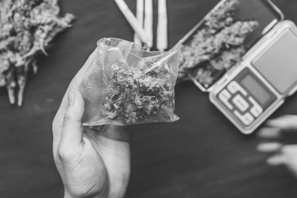Um traficante de drogas tem um pacote de maconha em uma maconha escura preto e branco — Fotografia de Stock