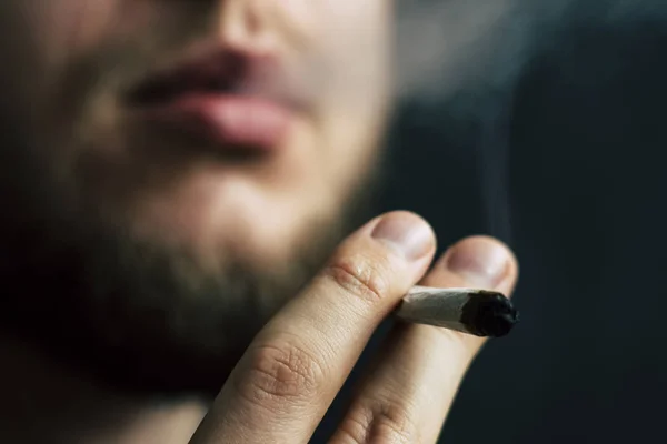 Конопля, косяк в руках, человек курит. Дым на черном фоне. Концепции использования медицинской марихуаны и легализации марихуаны . — стоковое фото