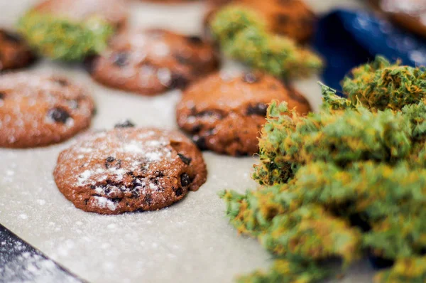 Koekjes met cannabis en toppen van marihuana op de tafel. Concept van het koken met cannabis kruid. Behandeling van medische marihuana voor gebruik in levensmiddelen op een witte achtergrond — Stockfoto