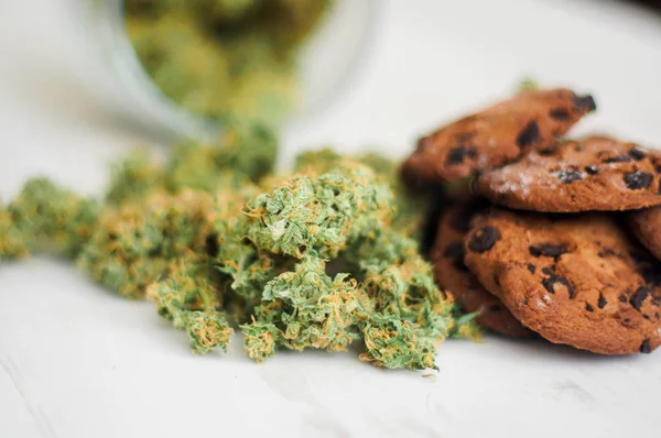 Cookies med cannabis och knoppar av marijuana på bordet. Begreppet matlagning med cannabisblad. Behandling av medicinsk marijuana för användning i livsmedel på en vit bakgrund — Stockfoto