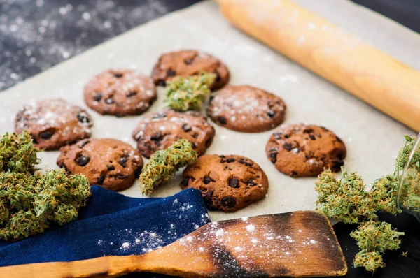 Biscoitos com maconha e botões de maconha na mesa. Conceito de cozinhar com erva de cannabis. Tratamento de maconha medicinal para uso em alimentos, em um fundo preto — Fotografia de Stock