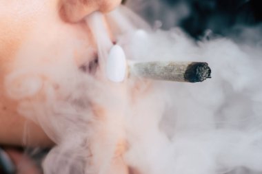 Bir kadın sigara ot esrar esrar ve onun elinde bir çakmak. Siyah bir arka plan üzerinde duman. Tıbbi esrar kullanım ve yasallaştırma esrar kavramları.