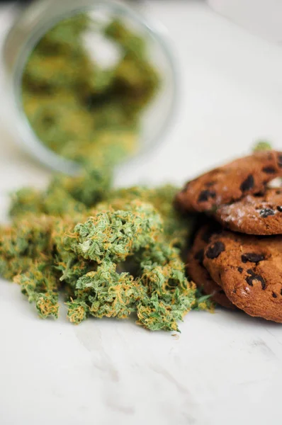 Cookies med cannabis och knoppar av marijuana på bordet. Begreppet matlagning med cannabisblad. Behandling av medicinsk marijuana för användning i livsmedel på en vit bakgrund — Stockfoto