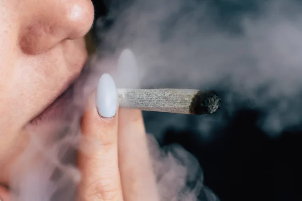 一个女人抽大麻, 一个关节和他手中的打火机。黑色背景下的烟雾。医用大麻的概念与大麻合法化. — 图库照片