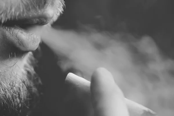 Kouří konopí plevel, společné a zapalovač ve svých rukou. Kouř na černém pozadí. Koncepce užívání lékařské marihuany a legalizace konopí. Černá a bílá — Stock fotografie